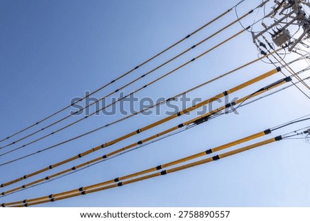 Blue sky with multiple power lines and utility pole creating diagonal composition