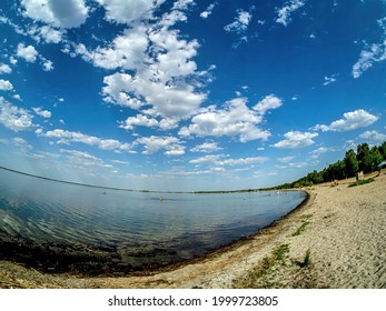 blue sky over the lake, light clouds, water, a strip of sandy beach, fisheye lens
