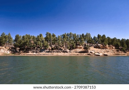 Blue sky over pine trees and rocks across the water at Keyhole State Park in Wyoming. 
