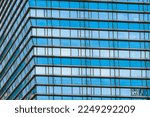 The blue sky is reflected in the windows of a modern office building. Architecture and exterior of contemporary houses