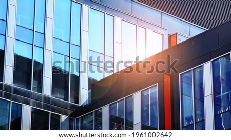 Blue sky reflection in glass facade of building. View of office building windows close up with sunrise, reflection and perspective..Bright sunny day with sunbeams on the blue sky. Velvia graphic filte