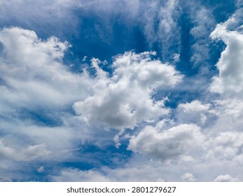 Blue sky showing an array of white cloud formations and wispy streaks, creating a dynamic and expansive atmospheric scene