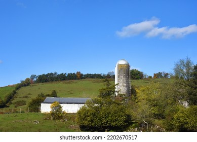 Blue Sky Sits Over Small Farm With White Barn And Silo.  Appalachian Mountain Rises In Back With A Small Line Of Trees.