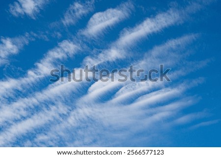 A blue sky with thin, wispy clouds arranged in parallel lines.