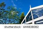 Blue sky, trees and clouds reflected in a garden conservatory.