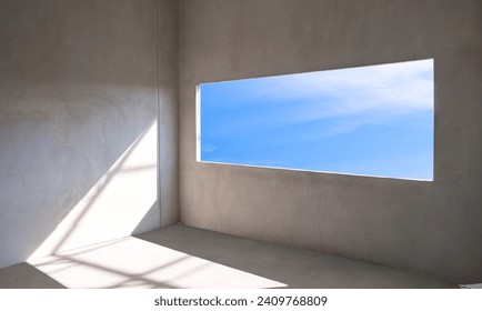 Blue sky view inside of Panoramic Window Frame with sunlight shining through into concrete Wall Room of incomplete modern House Building Structure in Construction Site