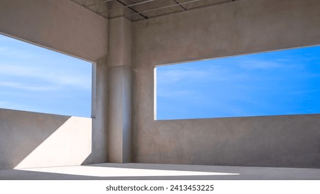 Blue sky view inside of two Panoramic Window Frames with sunlight shining through into incomplete concrete Wall Room of modern House Building Structure in Construction Site