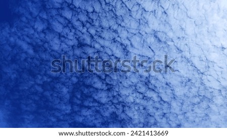 a blue sky and white altocumulus cloud
