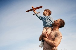 Blue Sky With White Cloud. Father Is Holding Son That Playing With Toy Plane.