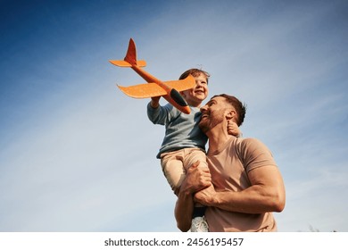 Blue sky with white cloud. Father is holding son that playing with toy plane. - Powered by Shutterstock