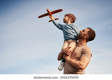 Blue sky with white cloud. Father is holding son that playing with toy plane.