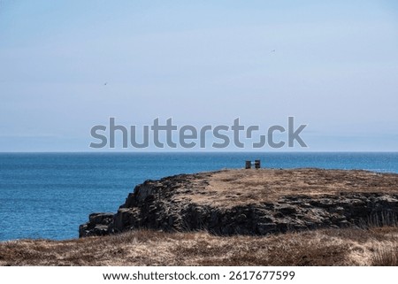 Blue sky, white clouds, calm sea. Cliff coast, lonely chair, peaceful life. -Elliston, Newfoundland and Labrador, Canada. 