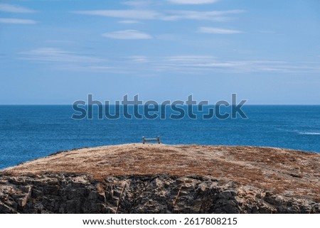 Blue sky, white clouds, calm sea. Cliff coast, lonely chair, peaceful life. -Elliston, Newfoundland and Labrador, Canada. 