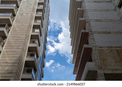 Blue sky with white clouds in the gap between gray skyscrapers