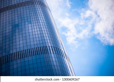 Blue sky and white clouds are reflected on the glass curtain walls of urban commercial buildings.