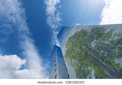Blue skyscraper streetart with painted Chestnut tree and rectangular color fields pattern abstract painted mural towering into the blue cloudy summer sky in Langen, Hesse, Germany, copy space