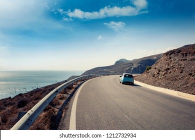 Blue small car rides along a serpentine mountain road along the sea, Kos island, Greece