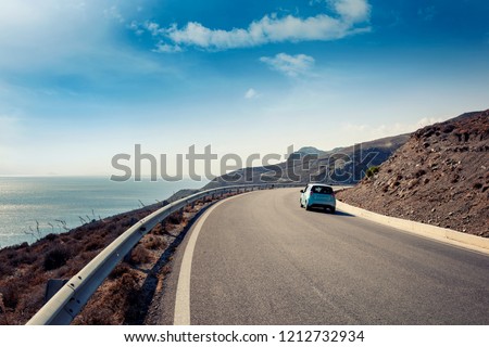 Blue small car rides along a serpentine mountain road along the sea, Kos island, Greece