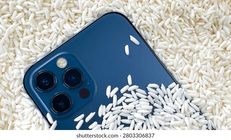 A blue smartphone camera module nestled among grains of dry white rice. This concept is designed for emergency drying of wet mobile devices, repair, and protection of electronics.