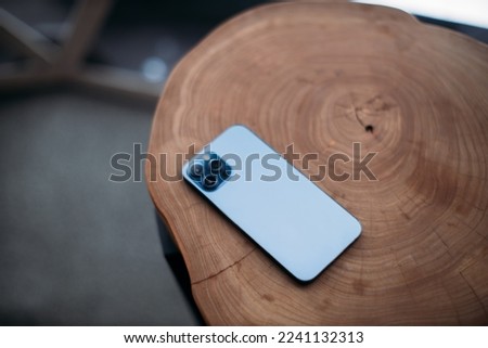 blue smartphone on a wooden table. winter outside the window