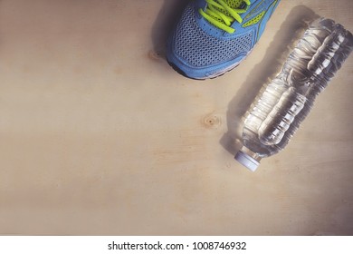 Blue Sneakers And 1 Bottle Of Water. Placed On A Light Brown Wood Floor. Concept: Sports ,Fitness , Running ,Health  And Exercise. Zumba Dance Workout For Weight Loss.