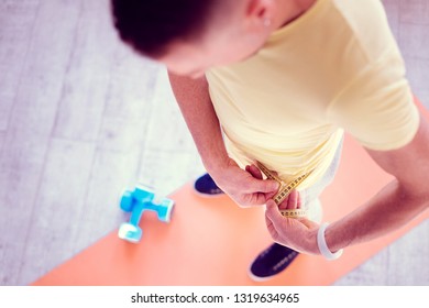 Blue sneakers. Blonde-haired strong and athletic man wearing blue sneakers measuring his waistline after sport time - Powered by Shutterstock