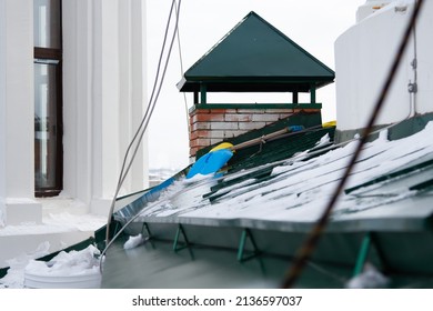 Blue Snow Shovel On A Green Roof