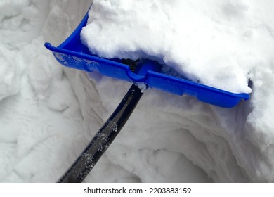 Blue snow shovel stuck in the snow before cleaning the path around the country house after a huge snowfall. Snow trench. Domestic labour and chores - Shutterstock ID 2203883159