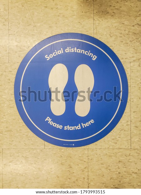 Blue social distancing\
marker on floor
