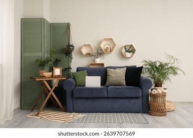 Blue sofa, folding screen and table near white wall in interior of living room