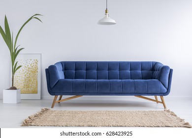 Blue sofa and wicker carpet in white simple living room - Shutterstock ID 628423925