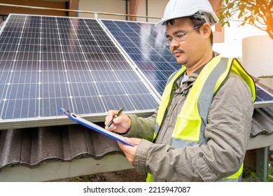 Blue Solar Photo Voltaic Panels System Of Apartment Building On Sunny Day. Renewable Ecological Green Energy. Maintenance Panels Collect Solar Energy. Engineer Holding Clip Board