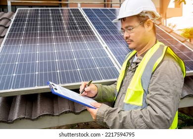 Blue Solar Photo Voltaic Panels System Of Apartment Building On Sunny Day. Renewable Ecological Green Energy. Maintenance Panels Collect Solar Energy. Engineer Holding Clip Board