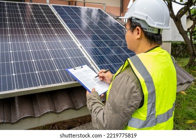 Blue Solar Photo Voltaic Panels System Of Apartment Building On Sunny Day. Renewable Ecological Green Energy. Maintenance Panels Collect Solar Energy. Engineer Holding Clip Board