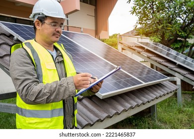 Blue Solar Photo Voltaic Panels System Of Apartment Building On Sunny Day. Renewable Ecological Green Energy. Maintenance Panels Collect Solar Energy. Engineer Holding Clip Board