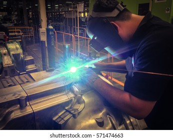 Blue Spark Light And Welding Mask From Asian Technician Man Manual Laser Welding At Surface Of Mold (soft Focus Background)