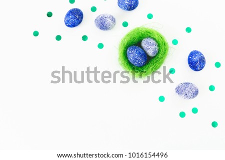 Blue Speckled Easter Egg and bright nest on white background. Flat lay. Top view. Easter concept with copy space