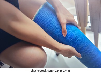 Blue Splint Knee. Bandaged Leg Cast And Toes After A Running Injury Accident.Young Woman In Blue Plaster Cast. Cropped Shot Of A Girl Holding Her Leg In Pain. Shin Splints.