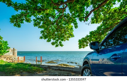 Blue sport SUV car parked by the tropical sea under umbrella tree. Summer vacation at the beach. Summer travel by car. Road trip. Automotive industry. Hybrid and electric car concept. Summer vibes.  - Powered by Shutterstock