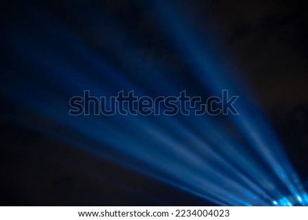 Blue spotlight rays with dark sky. Concert or festival or performance concept photo with copy space. Noise included. Selective focus.