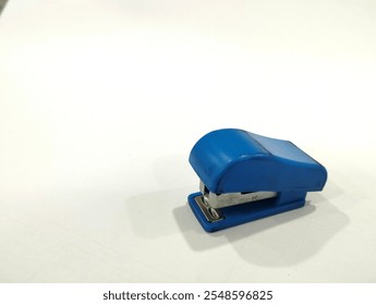 Blue stapler with blue background and empty space on the left side - Powered by Shutterstock