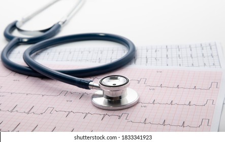 Blue Stethoscope on electrocardiogram (ECG) chart paper. ECG heart chart scan isolate on white. Healthcare insurance and medical background 