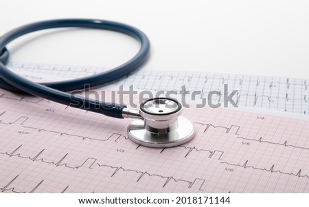 Blue Stethoscope on electrocardiogram (ECG) chart paper. ECG heart chart scan isolate on white. Healthcare insurance and medical background 