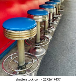 Blue stools in empty diner against red counter
