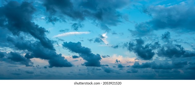 Blue stormy clouds blown by the strong wind across the sky at evening. Dramatic sky with torn dark clouds low over the horizon. Overcast skyscape panorama at blue hour. Wide windy weather cloudscape. - Shutterstock ID 2053921520