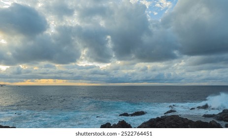 Blue stormy foamy waves crashing on a rocky shore at sunset. Buenavista del Norte, Santa Cruz de Tenerife, Spain. Weather landscape. Evening photography by the ocean. Cloudy sky and rocks on the coast - Powered by Shutterstock