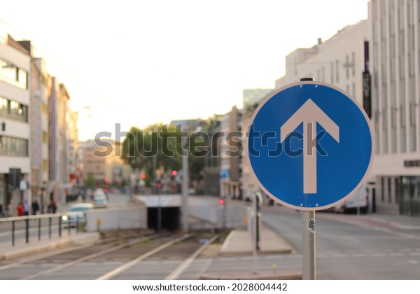 The blue\
straight sign in city centre of Dusseldorf in Germany showing the\
cars can only drive in this direction.\
