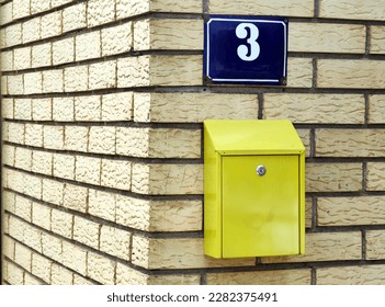 Blue street number 3 plate. Yellow home mail box and brick wall background. Pattern and texture. Minimalism. Around the corner. Stip, 2023 Macedonia