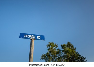 Blue street sign reading Hospital Road against blue sky background