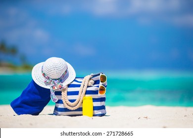 Blue stripe bag and towel, straw white hat, sunglasses, sunscreen bottle on exotic beach